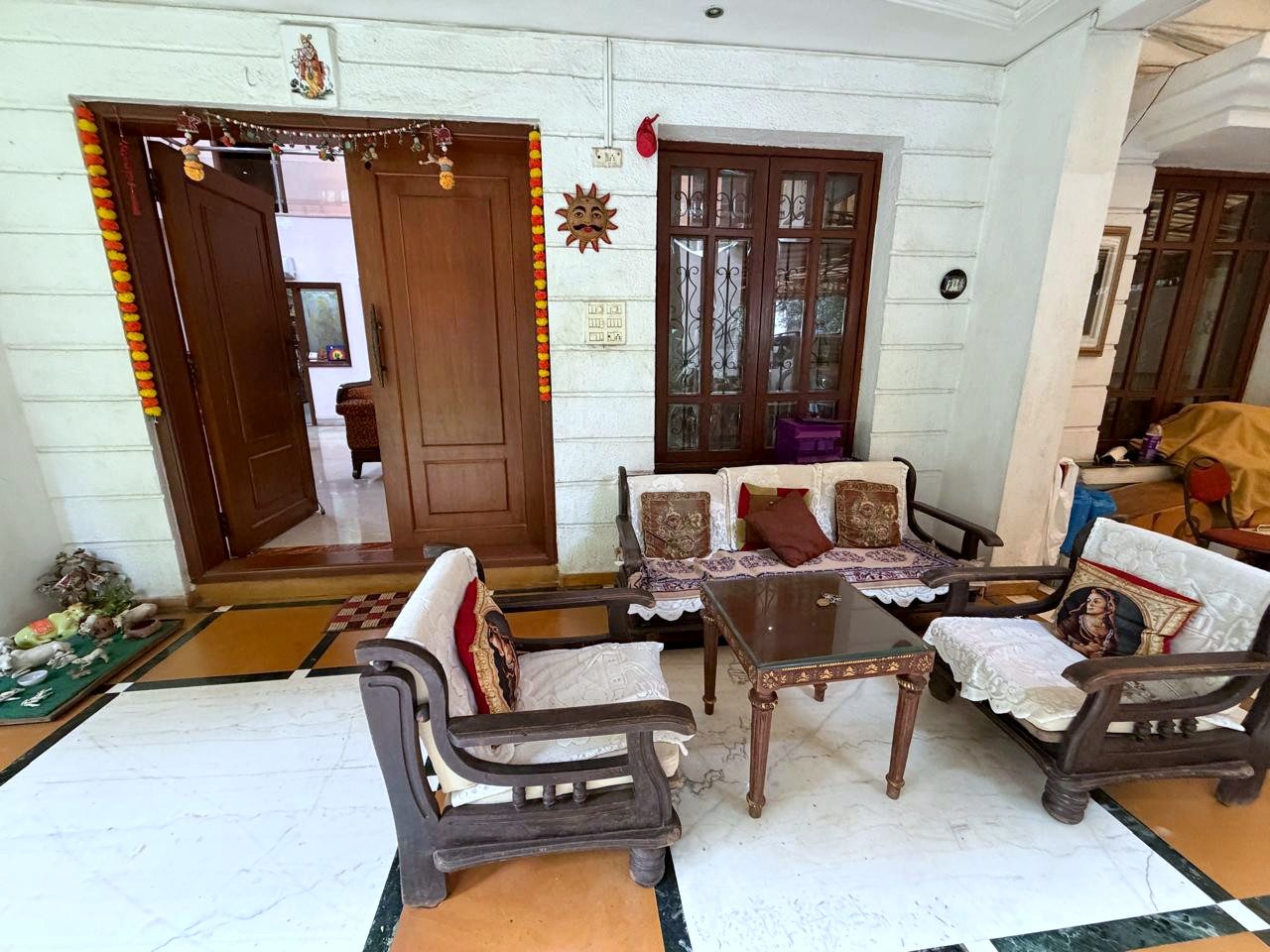 A furnished common living room with seating and tall wooden doors